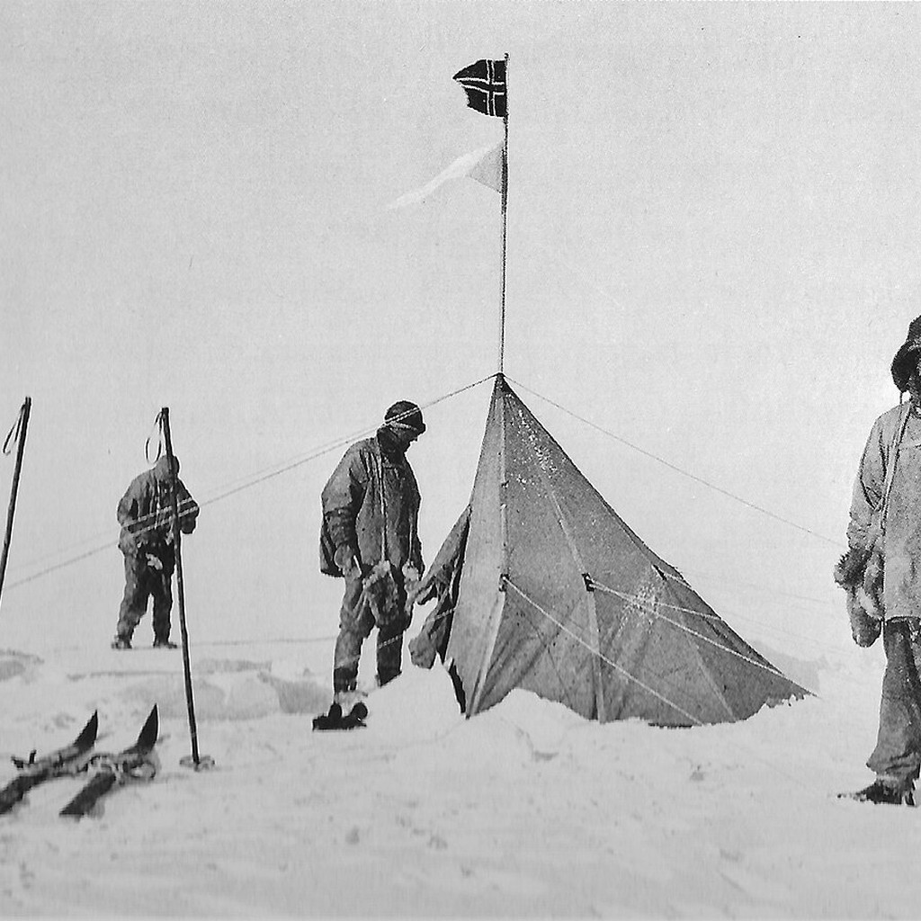 1912年1月18日、アムンセンが残したポルハイムのテントとノルウェー国旗の前に立つスコット隊。極点でノルウェー隊の到達記録を確認した場面。
