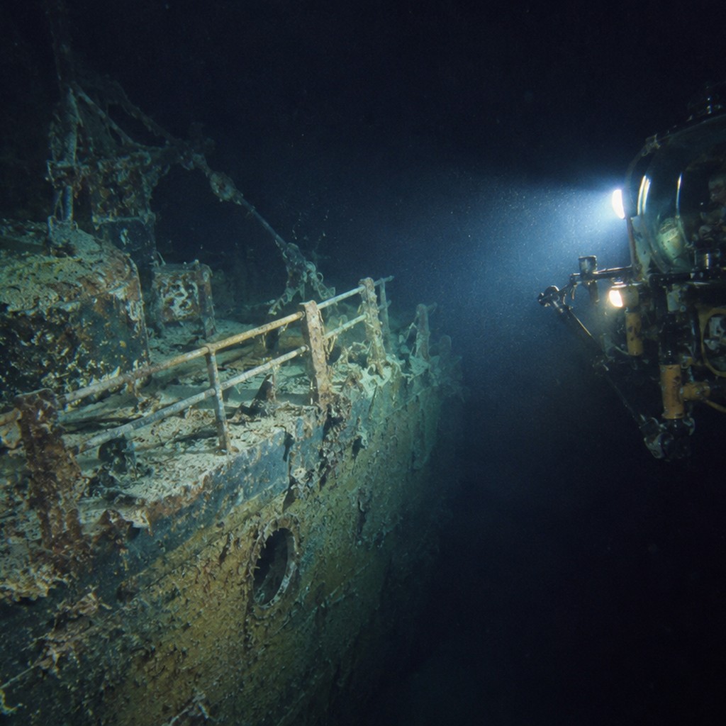 1980年代後半の深海探査で、有人潜水艇または小型探査機が沈没船の一部を探査灯で慎重に観察する。